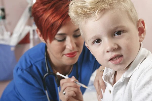Маленький мальчик наблюдает, как медсестра делает ему укол . — стоковое фото