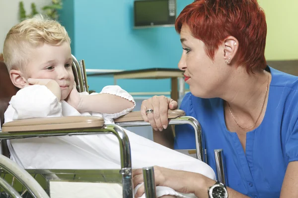 Un adorabile bambino sulla sedia a rotelle in ospedale con fare — Foto Stock