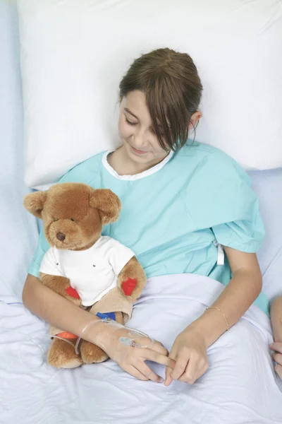 Meisje in ziekenhuisbed met teddy bear — Stockfoto