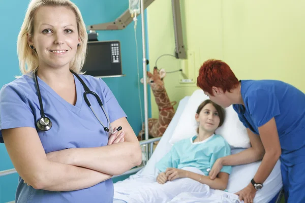 Liten flicka i sjukhussäng med sjuksköterskan — Stockfoto