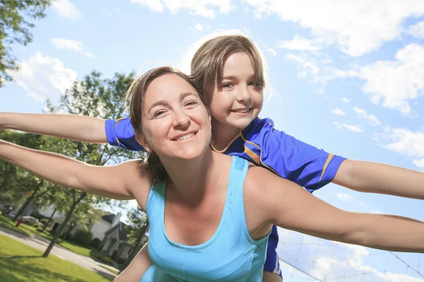 A mother with is daughter play soccer on kid back — Stock Photo, Image