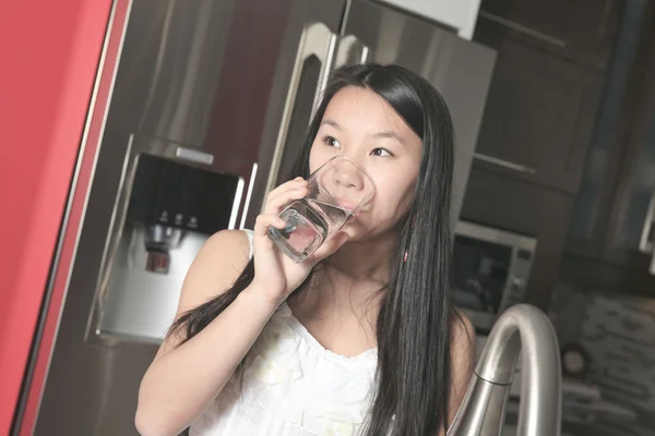 10 代の女の子が台所で水を飲む — ストック写真
