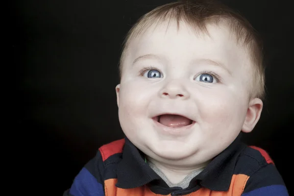 Un bebé joven y sonriente está mirando a la cámara aislada en un bla — Foto de Stock