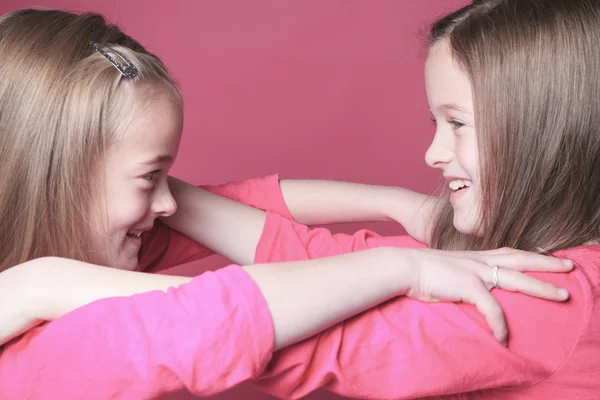 Jonge zus meisje vormt voor een foto geïsoleerd op roze — Stockfoto