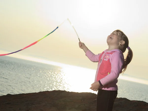 Bambina giocare con un bastone multicolore al tramonto — Foto Stock