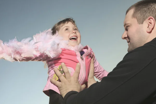 Una niña divertida jugar con es papá en la puesta del sol . — Foto de Stock