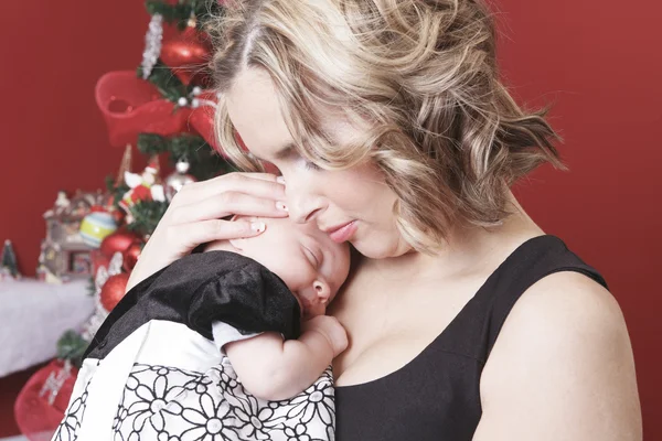 A christmas toddler with is mother in front of a fir. — Stock Photo, Image