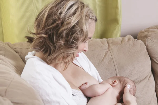 Una madre che nutre il suo bambino sul divano — Foto Stock