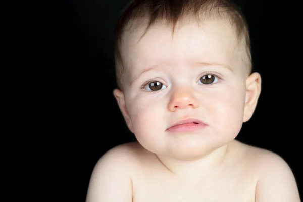 Dulce niño sentado en el estudio de fondo negro — Foto de Stock