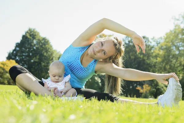 Eine Mutter, die an einem Sommertag mit Baby trainiert — Stockfoto