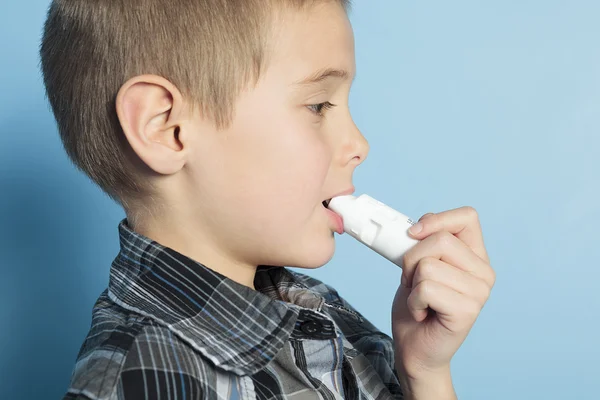 Um menino com asma é inalador sobre fundo azul — Fotografia de Stock