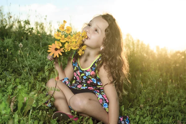 Holčička v západu slunce s květinou — Stock fotografie