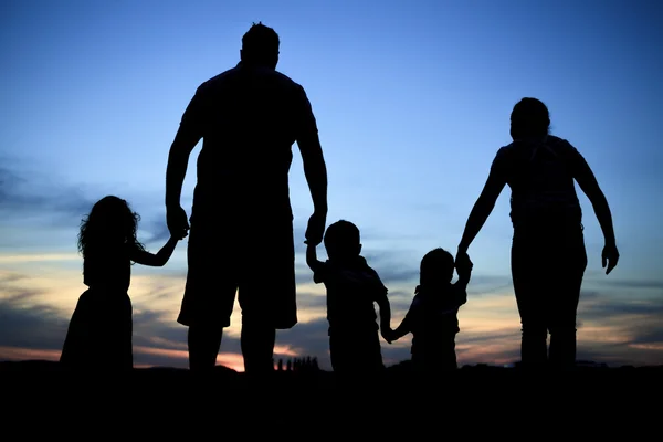 Silhuetten av en ung familj med några childs ständiga — Stockfoto