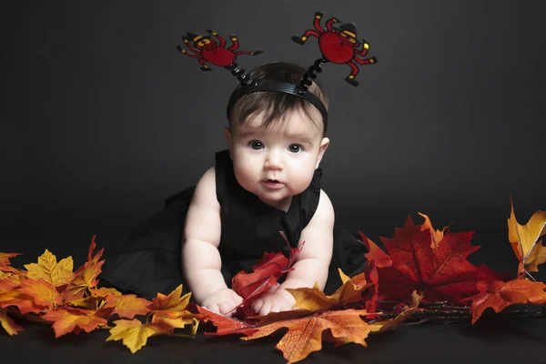 Sweet laughing baby girl playing with a huge pumpkin wearing a knitted pumpkin hat on white background — Stock Photo, Image