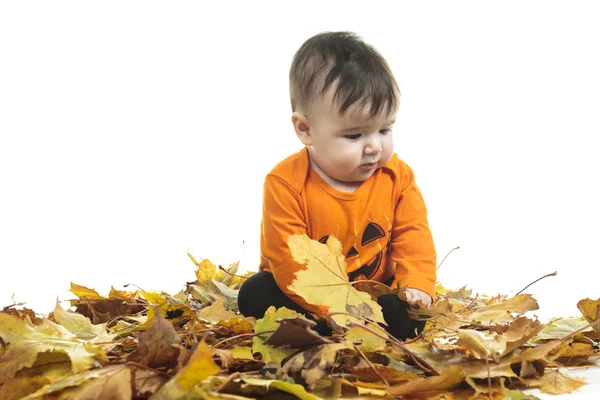 Sweet laughing baby girl playing with a huge pumpkin wearing a knitted pumpkin hat on white background — Stock Photo, Image