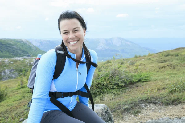 Female hiker with backpack walking and smiling on a country trai — Stock Photo, Image