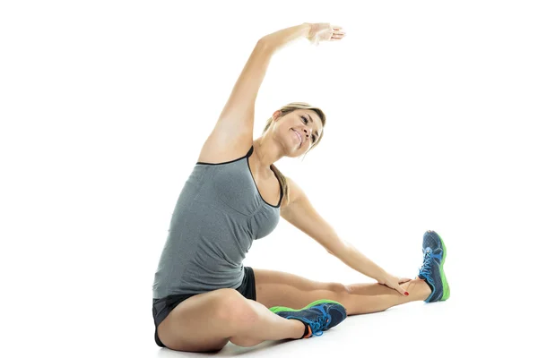 Fit woman stretching her leg to warm up - isolated over white background — Stock Photo, Image