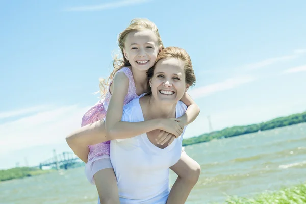 Young girl hugging her mother piggyback style — Stock Photo, Image