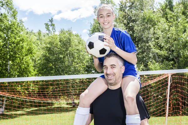 Девочка-подросток с отцом играют в футбол в прекрасный день — стоковое фото