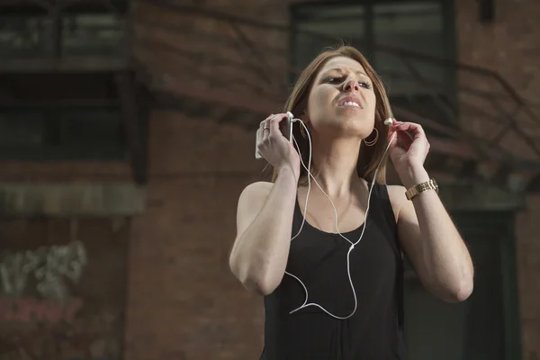 Young beautiful woman in town listening music earphone — Zdjęcie stockowe