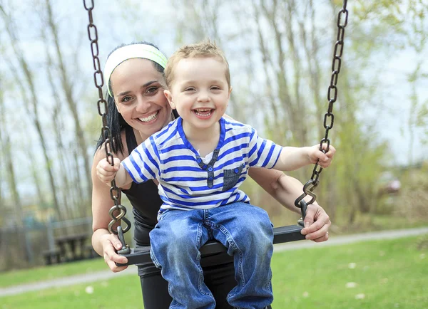 Mother pushing son on swing — Stock Photo, Image