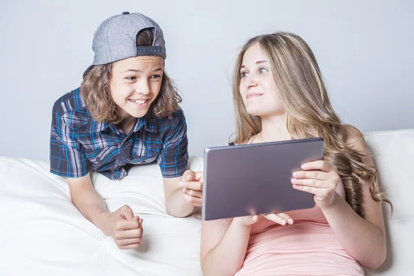 Brother and daughter using digital tablet on sofa at home — Stockfoto