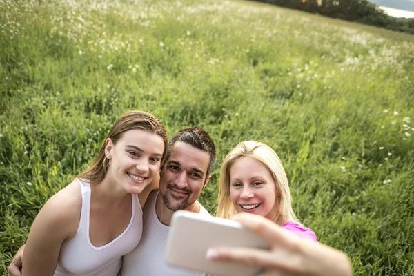 Amigos felizes passar tempo livre juntos em um campo — Fotografia de Stock