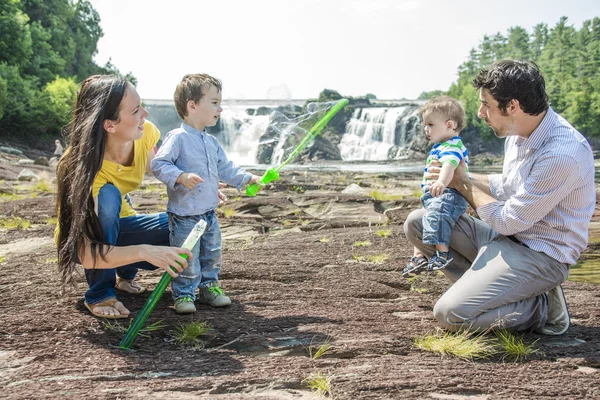 Happy family of four blows bubbles outside — Stock Photo, Image