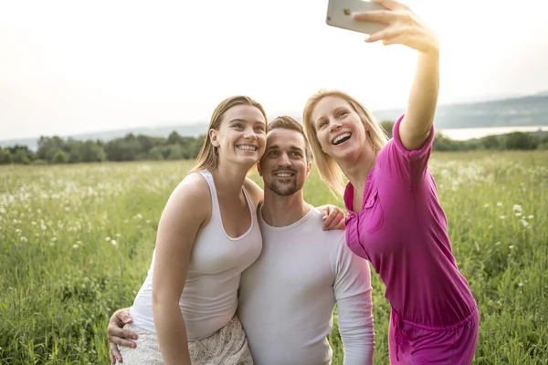 Amigos felizes passar tempo livre juntos em um campo — Fotografia de Stock