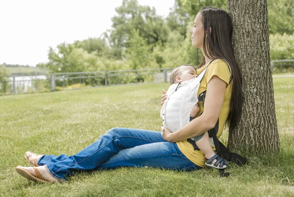 Happy woman and child leaning on tree in city park — Stock Photo, Image