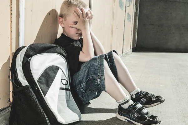 A very sad boy in school playground — Stock Photo, Image