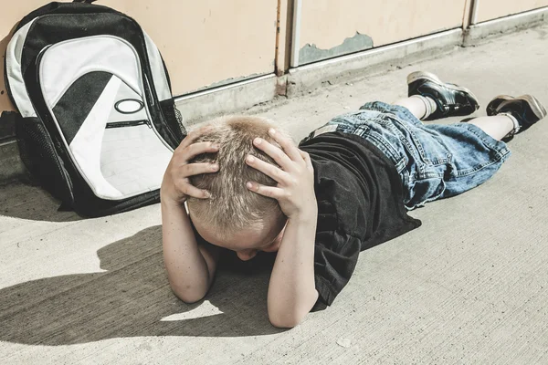 A very sad boy in school playground — Stock Photo, Image