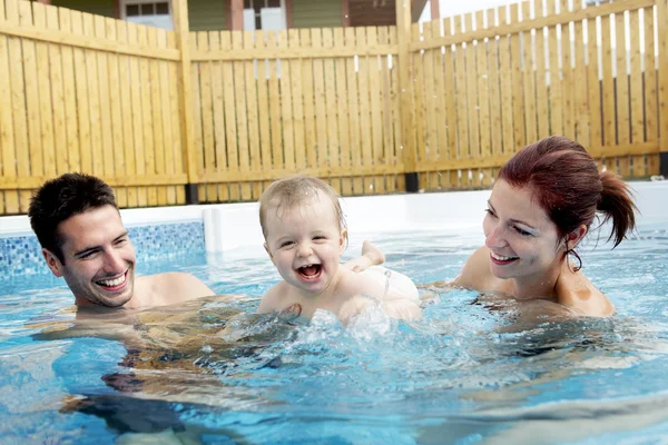 Porträt einer jungen Familie mit Baby und Kleinkind im Schwimmbad — Stockfoto