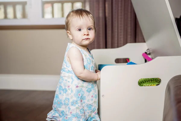 Pequena menina bonita na frente de sua caixa de brinquedos — Fotografia de Stock