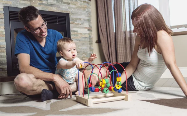 Ouders baby zittend op de vloer spelen met speelgoed — Stockfoto