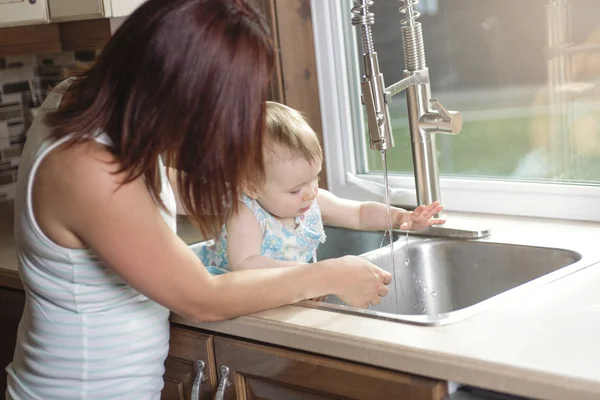 Jonge moeder en haar dochter schattig peuter in keuken — Stockfoto