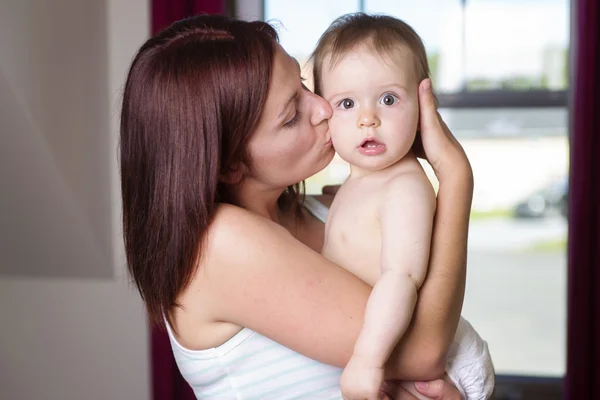 Happy mother holding baby boy at home in bedroom — Stock Photo, Image
