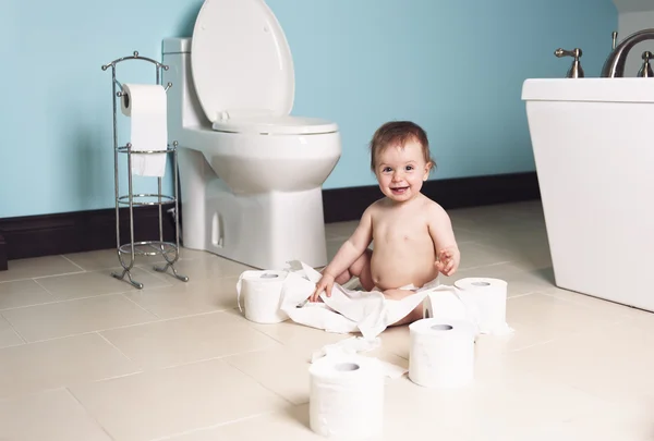 Criança rasgando papel higiênico no banheiro — Fotografia de Stock