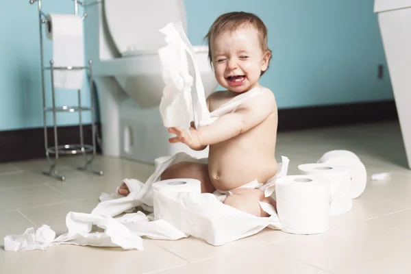 Criança rasgando papel higiênico no banheiro — Fotografia de Stock