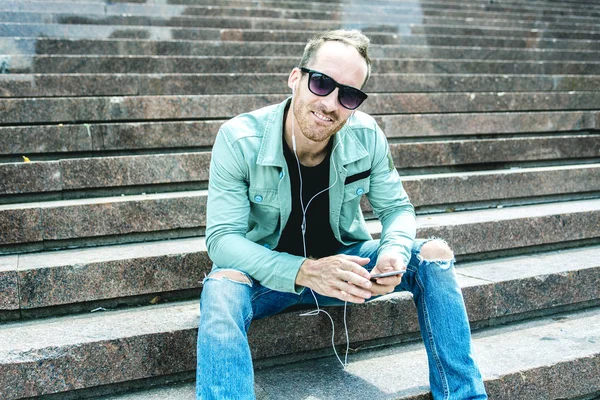 Man luisteren naar de muziek met earbuds van een slimme telefoon — Stockfoto