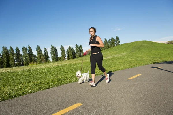 Vacker ung kvinna jogging med sin hund — Stockfoto