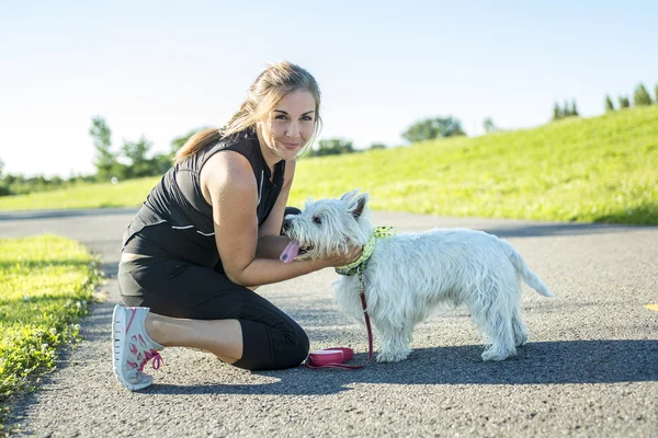 Hermosa joven mujer corriendo con su perro — Foto de Stock