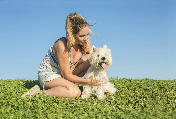 Portret pięknej dziewczyny, utrzymanie pies zewnątrz ładny biały West Highland — Zdjęcie stockowe