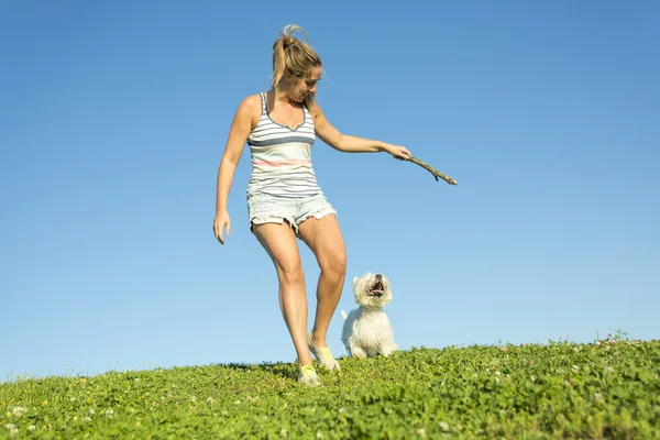 Portrett av en vakker jente som holder en pen, hvit West Highland hund utendørs – stockfoto