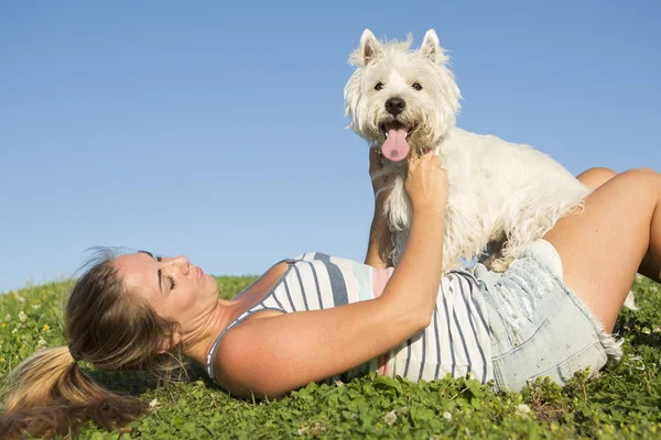Portret pięknej dziewczyny, utrzymanie pies zewnątrz ładny biały West Highland — Zdjęcie stockowe