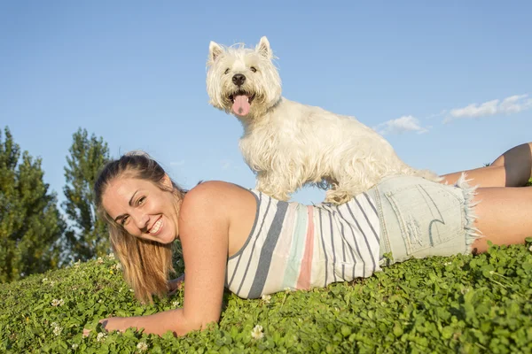 Portret pięknej dziewczyny, utrzymanie pies zewnątrz ładny biały West Highland — Zdjęcie stockowe