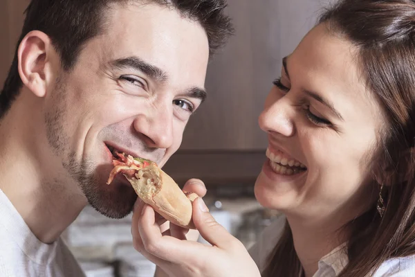 Happy young couple eating pizza at the kitchen — Stock Photo, Image