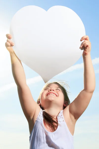 Young child holding heart over the sky — Stock Photo, Image