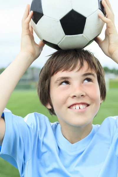 Jonge voetballer met bal op het veld — Stockfoto