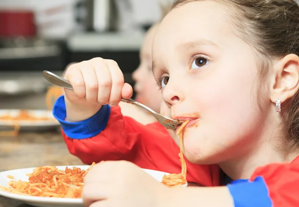Meisje eten pasta in de keukentafel — Stockfoto